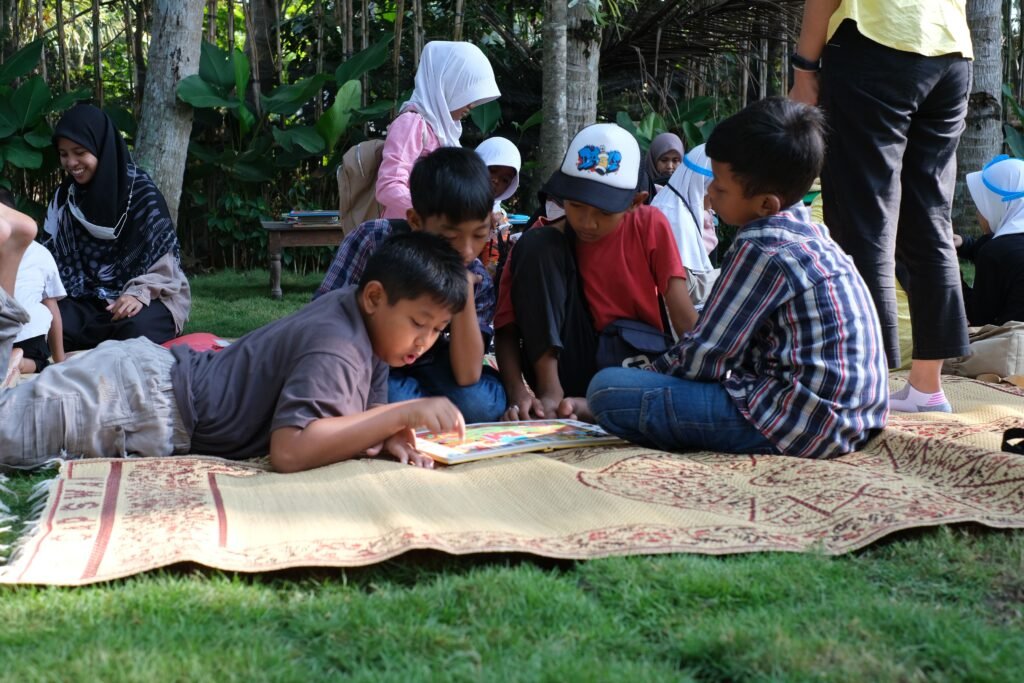A group of children enjoying a reading session outdoors during a picnic, fostering learning and friendship.