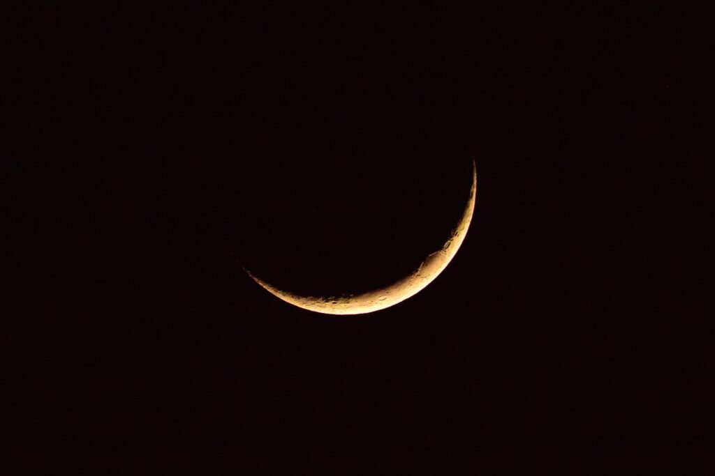 Astronomical natural background with bright yellow crescent moon glowing on dark black sky