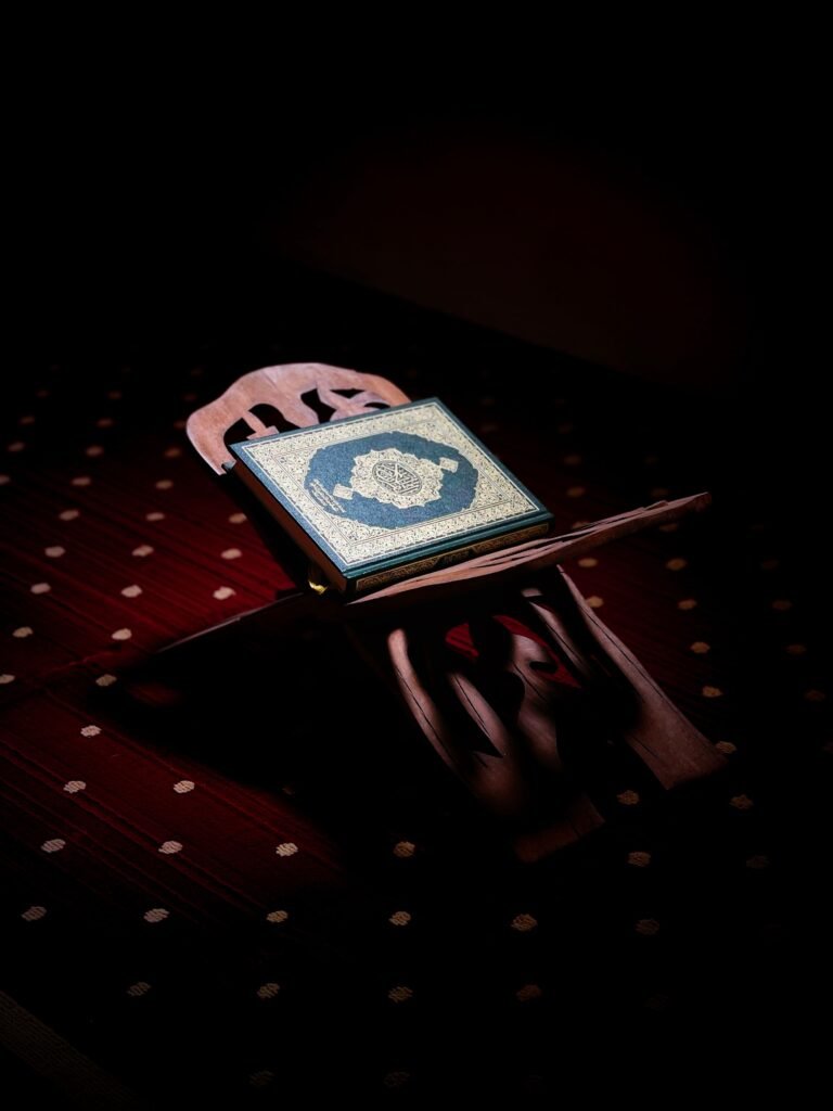 An intricately decorated book on a wooden stand in a dark setting, creating a serene atmosphere.
