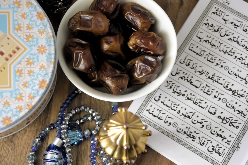 A bowl of fresh dates beside open Quran, symbolizing Ramadan fasting traditions.